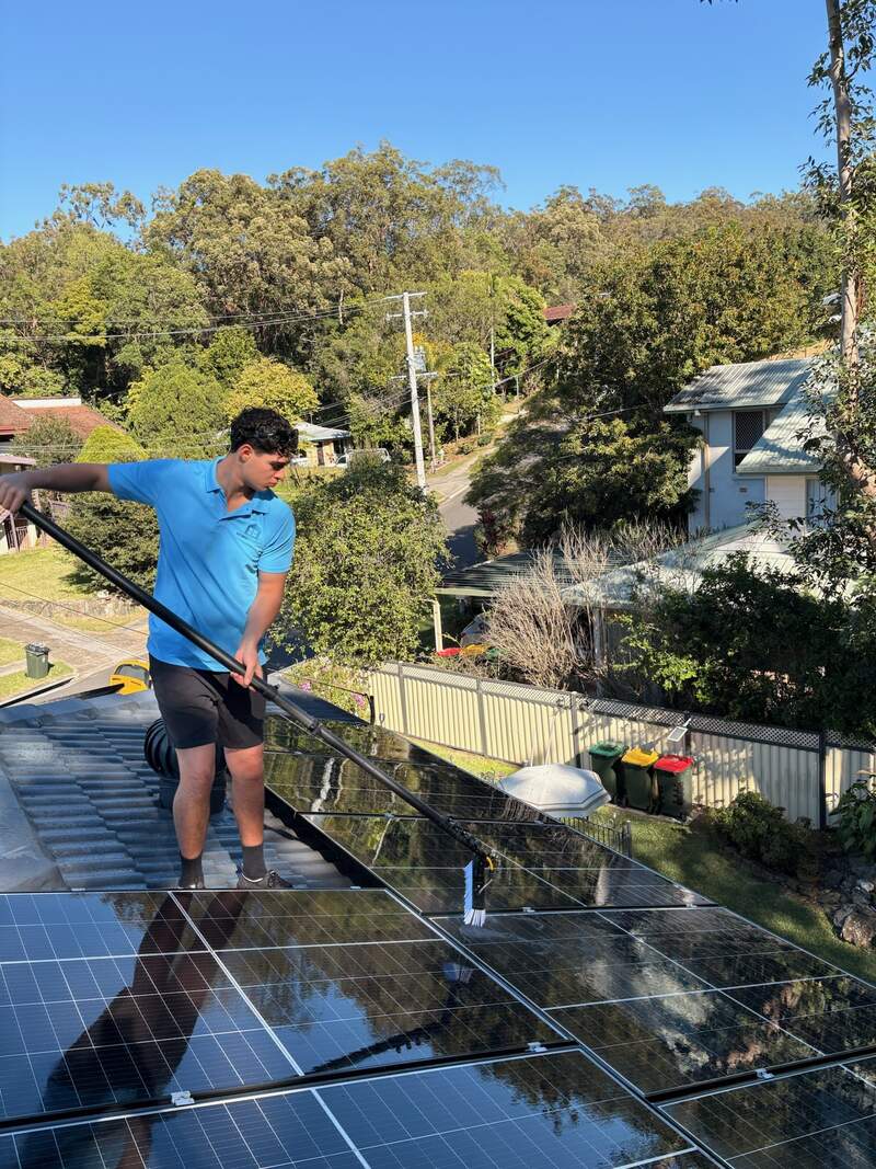 Home Boost team member cleaning solar panels with water-fed pole